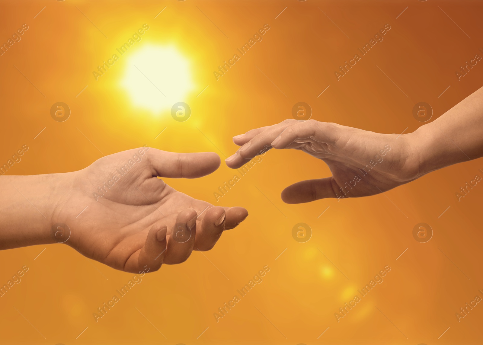 Image of Man and woman reaching to each other against sky with bright sun at sunset, closeup of hands