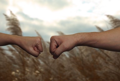 Image of Man and woman making fist bump in nature, closeup of hands