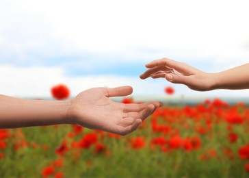 Image of Man and woman reaching to each other against flowering field, closeup of hands