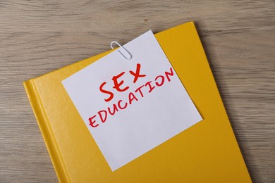 Image of Sex Education inscription in note paper attached to notebook on wooden table, top view