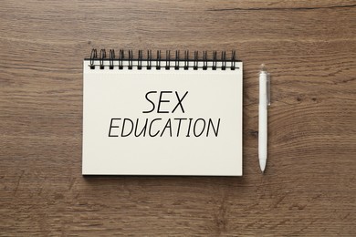 Image of Sex Education inscription in notebook and pen on wooden table, top view