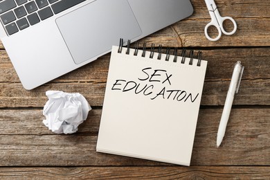 Image of Sex Education inscription in notebook, stationery and laptop on wooden table, top view