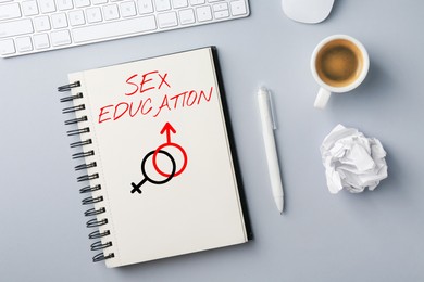Image of Sex Education inscription, male and female symbols in notebook, pen and coffee on grey table, top view