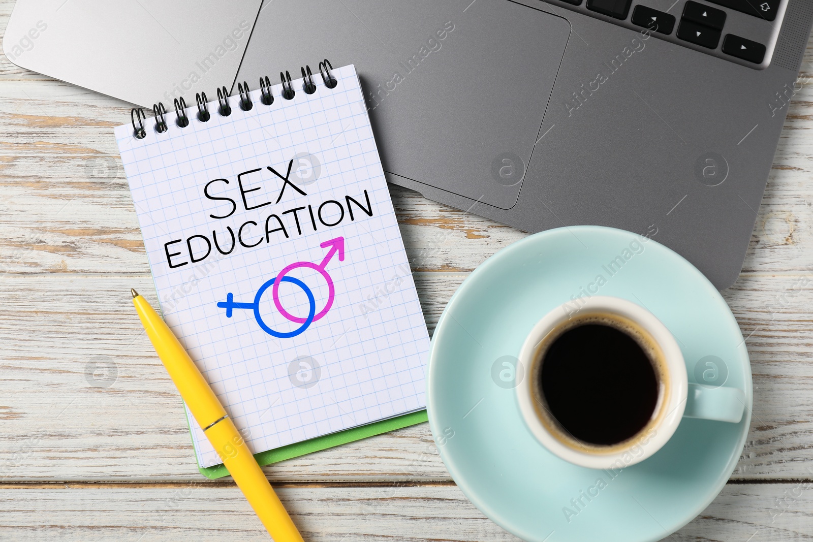 Sex Education inscription, male and female symbols in notebook, pen, coffee and laptop on wooden table, top view Image of Sex Education inscription, male and female symbols in notebook, pen, coffee and laptop on wooden table, top view
