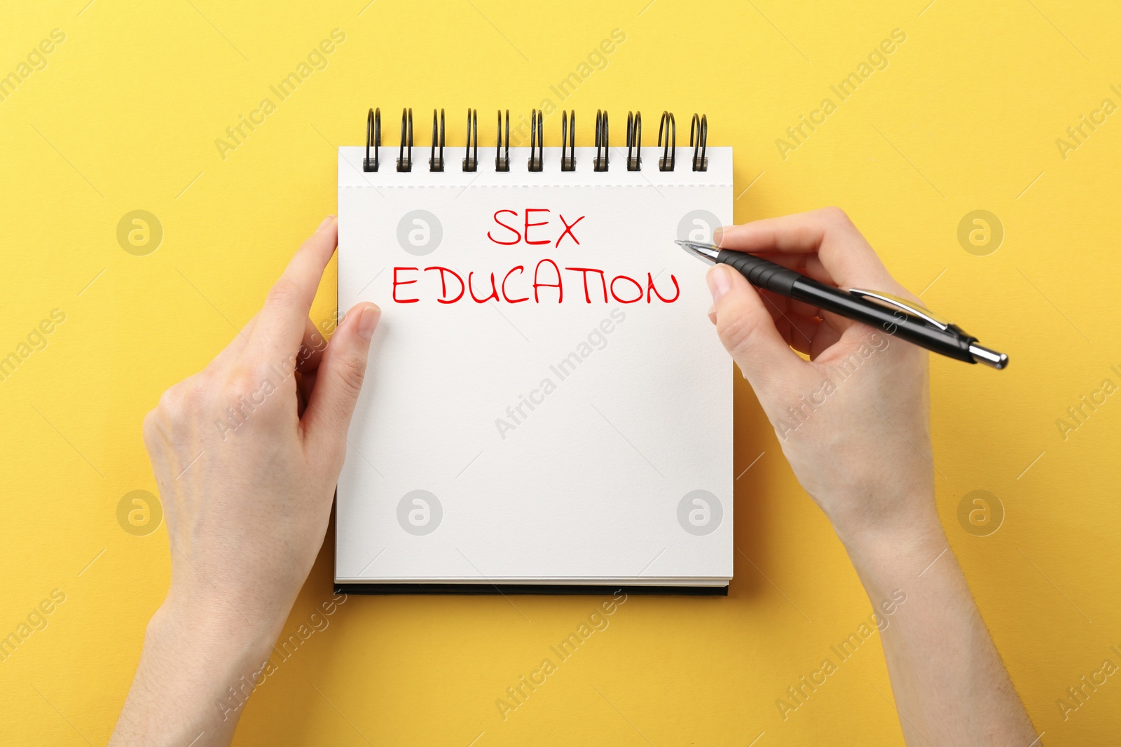 Woman writing Sex Education inscription in notebook on orange background, top view Image of Woman writing Sex Education inscription in notebook on orange background, top view