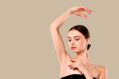 Image of Armpit epilation. Woman showing smooth underarms after hair removal against greige background