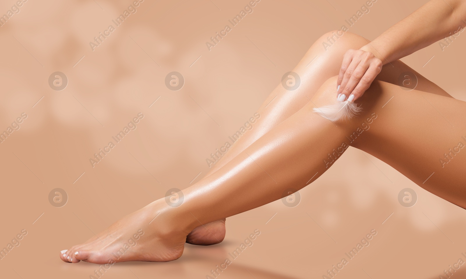 Image of Leg epilation. Woman touching her smooth skin after hair removal with feather against dark beige background, closeup.