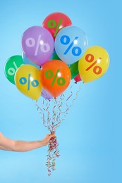 Image of Balloons with percent signs in man's hand on light blue background. Hot sale, special offer