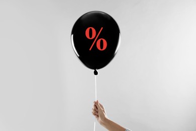 Image of Balloon with percent sign in woman's hand on light grey background. Hot sale, special offer