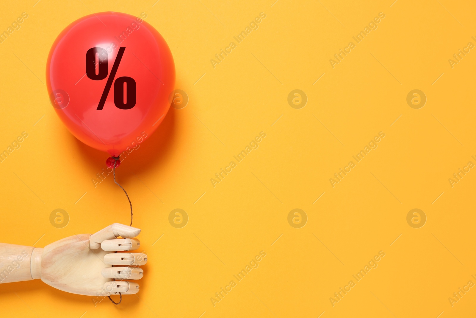 Red balloon with percent sign in mannequin's hand on orange background. Hot sale, special offer Image of Red balloon with percent sign in mannequin's hand on orange background. Hot sale, special offer