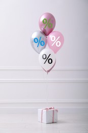 Image of Balloons with percent signs and gift box in room. Hot sale, special offer