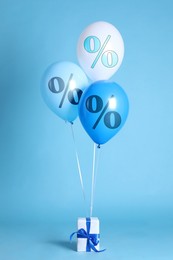 Image of Balloons with percent signs and gift box on light blue background. Hot sale, special offer