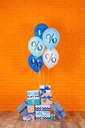 Image of Balloons and gift boxes near orange brick wall. Hot sale, special offer