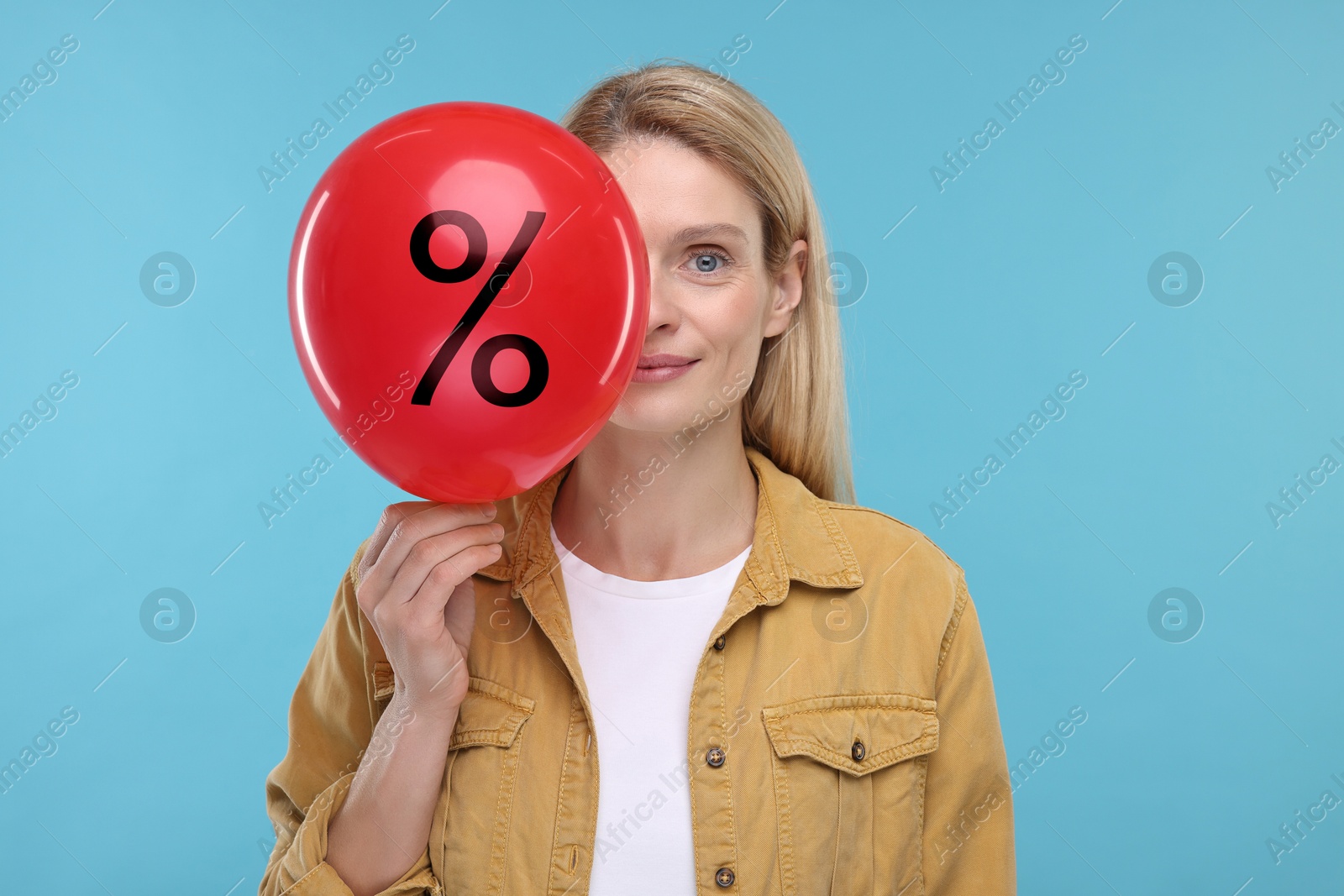 Woman holding balloon with percent sign near her face against light blue background. Hot sale, special offer Image of Woman holding balloon with percent sign near her face against light blue background. Hot sale, special offer
