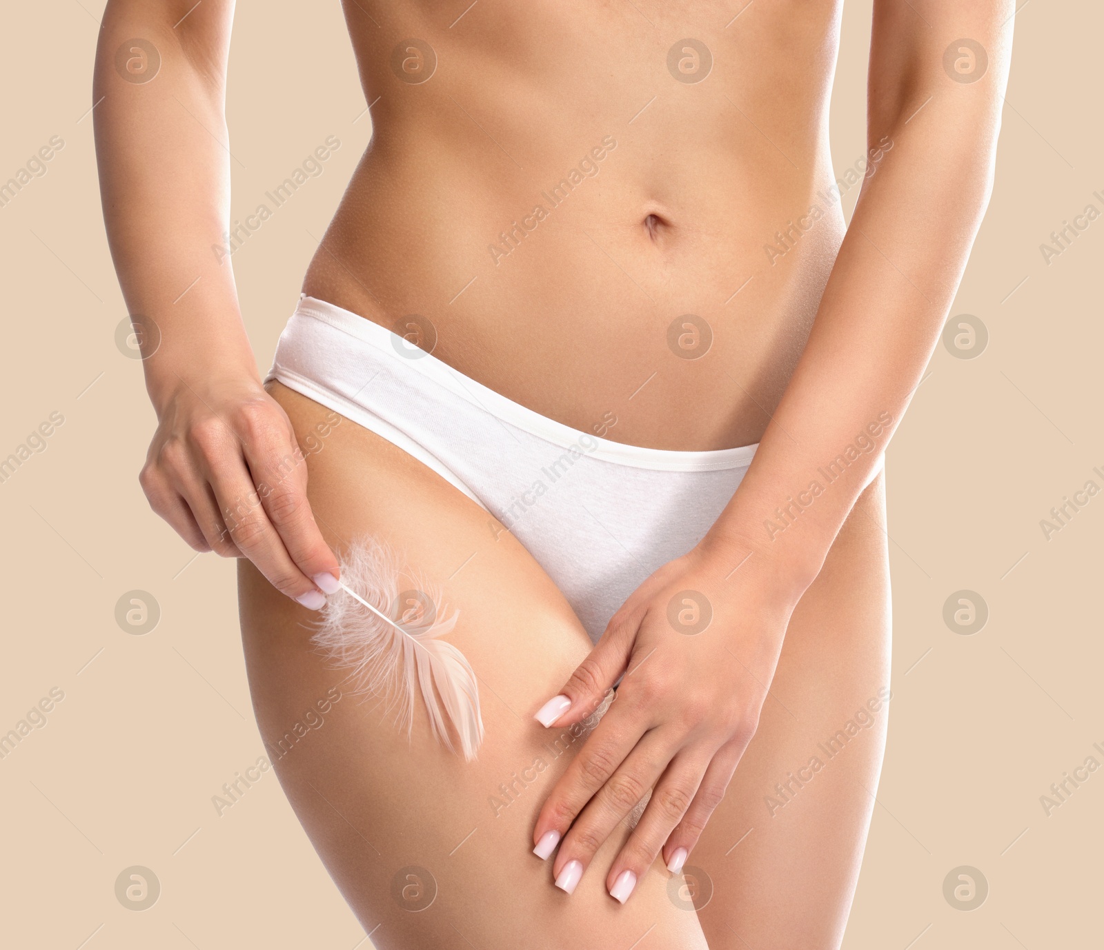 Image of Epilation. Woman touching her smooth skin after hair removal with feather against beige background, closeup.