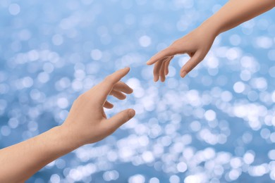 Image of Man and woman reaching to each other against seascape, closeup of hands