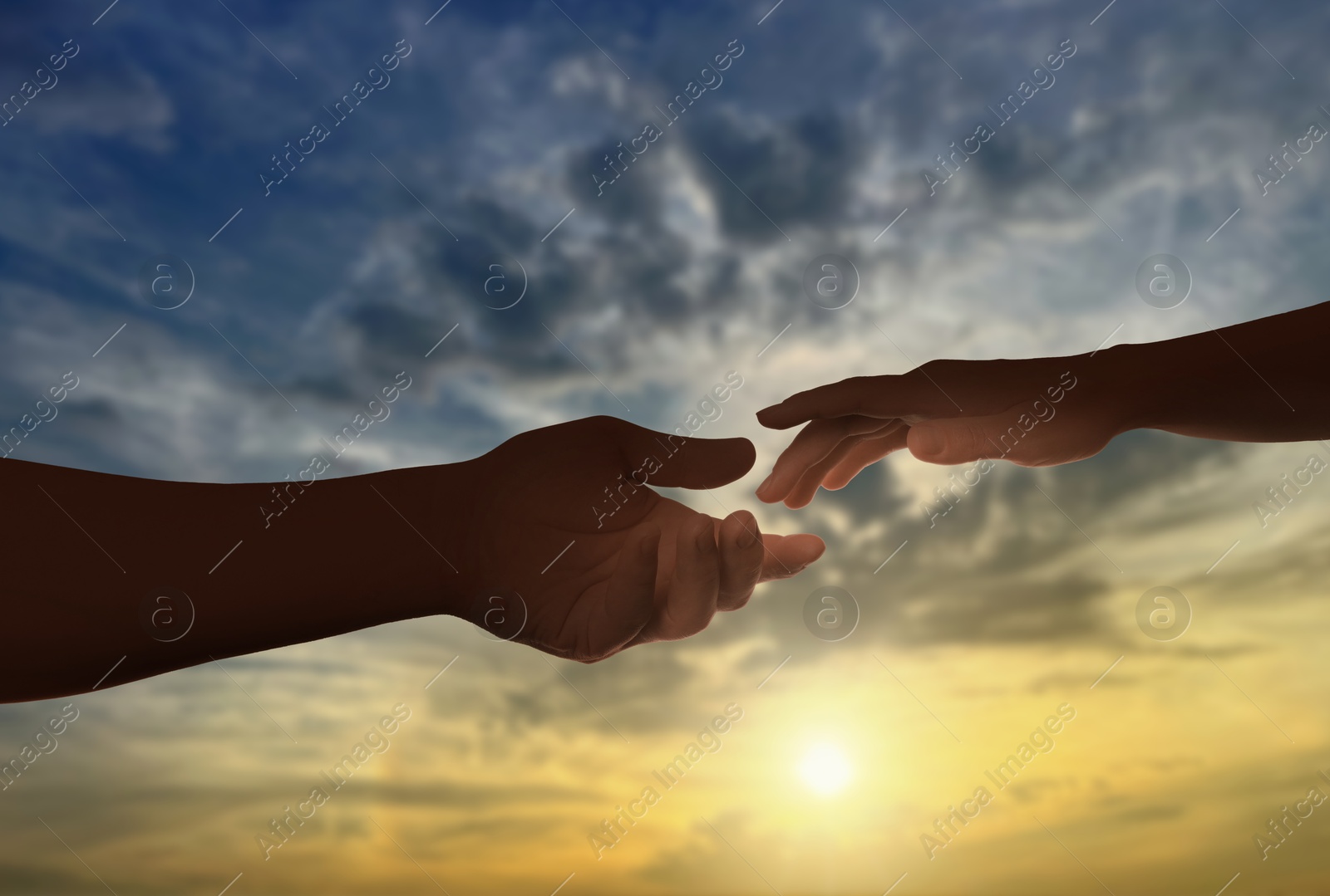Man and woman reaching to each other against sly at sunset, closeup of hands Image of Man and woman reaching to each other against sly at sunset, closeup of hands
