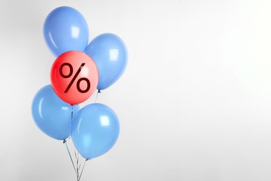 Image of Red balloon with percent sign among light blue ones against light background. Hot sale, special offer