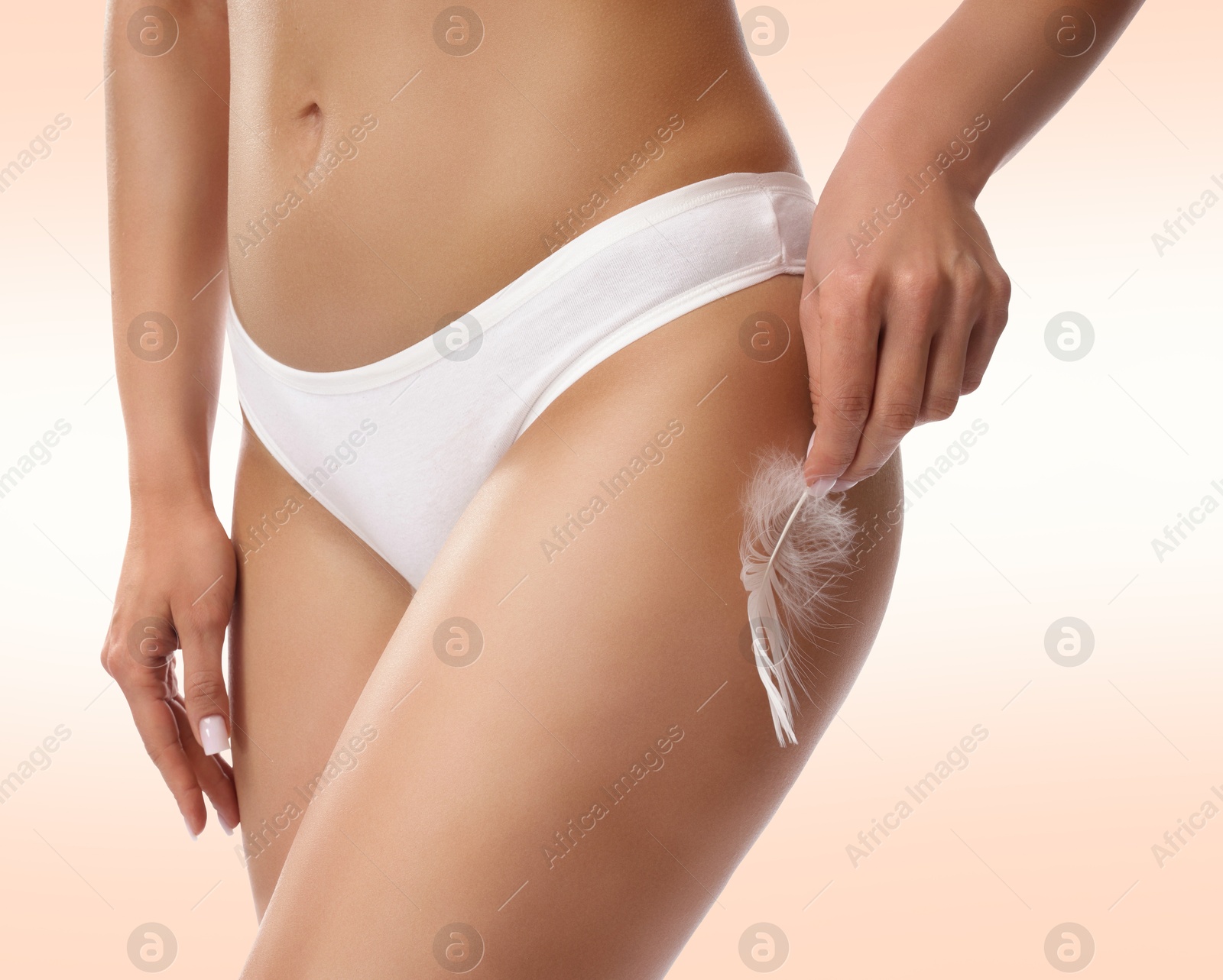 Epilation. Woman touching her smooth skin after hair removal with feather against beige background, closeup. Image of Epilation. Woman touching her smooth skin after hair removal with feather against beige background, closeup.