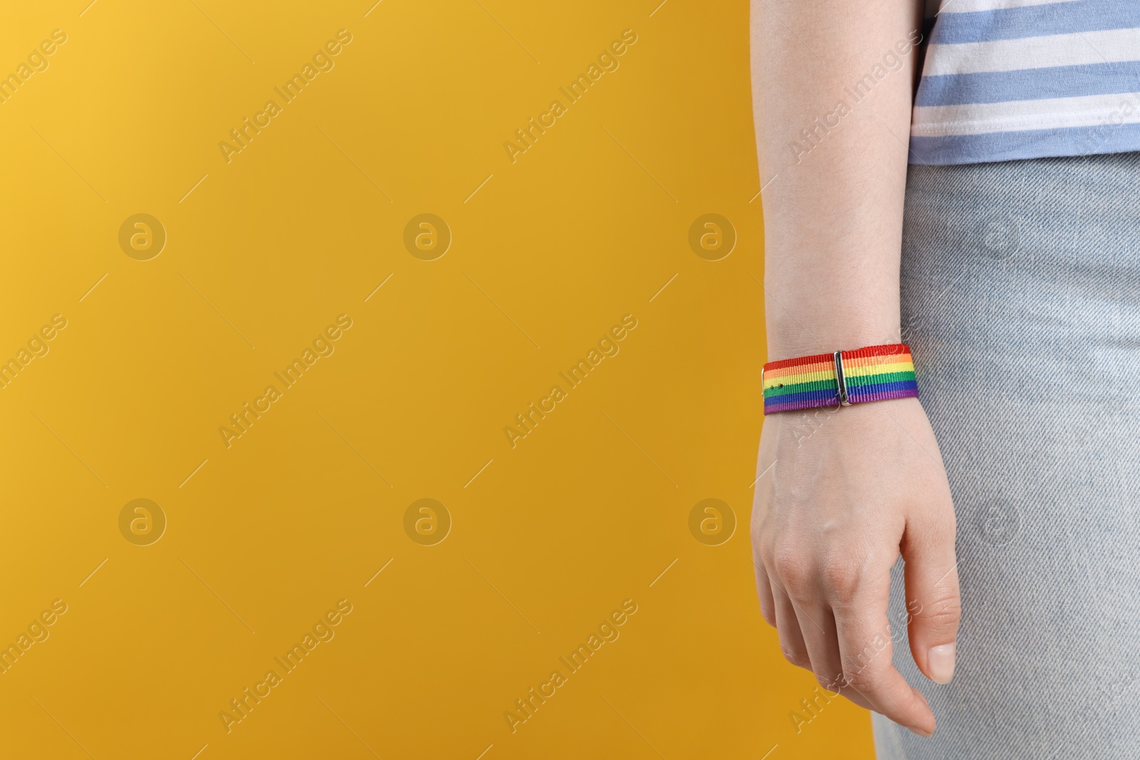 LGBT concept. Woman in rainbow wristband on yellow background, closeup. Space for text Photo of LGBT concept. Woman in rainbow wristband on yellow background, closeup. Space for text