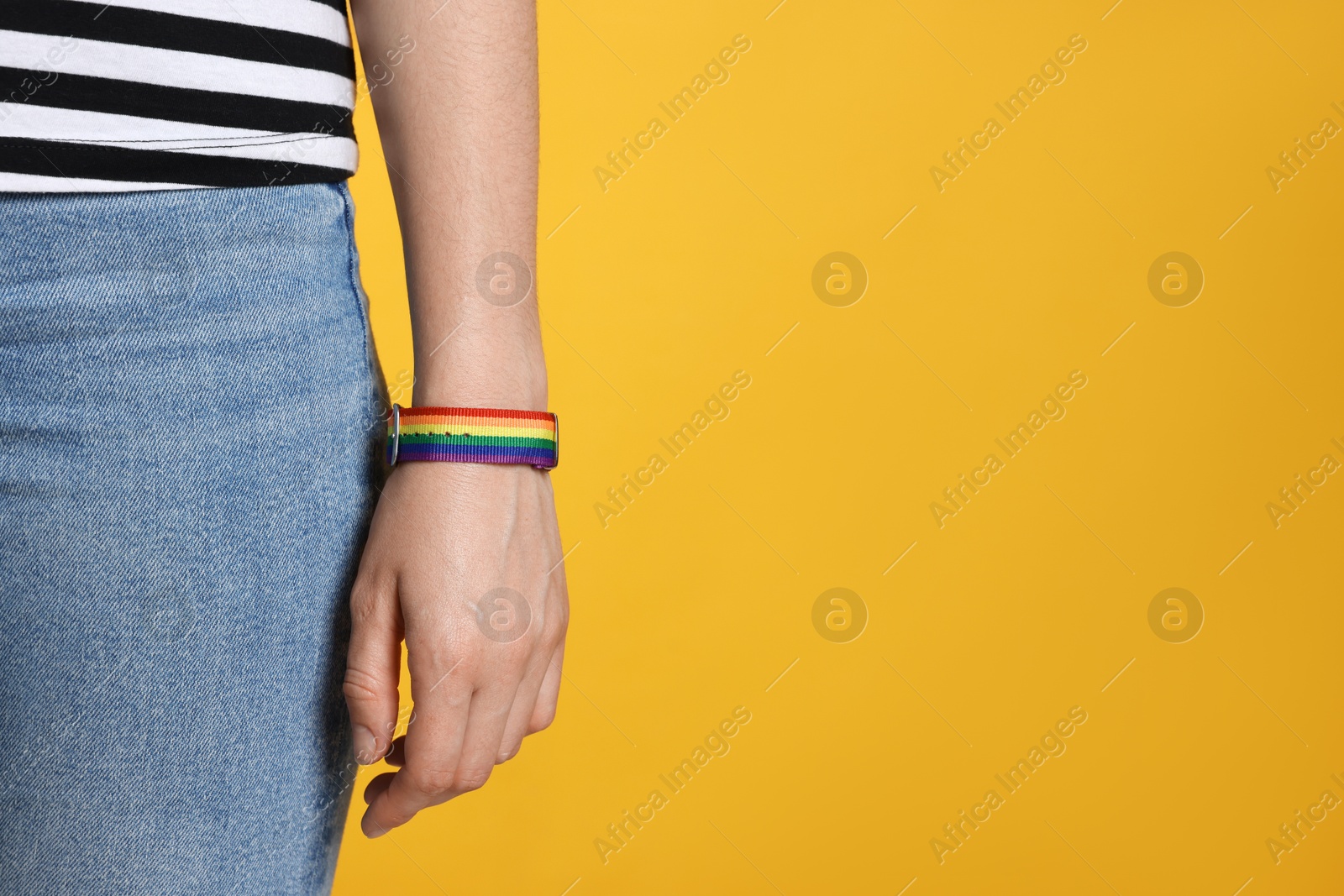 LGBT concept. Woman in rainbow wristband on yellow background, closeup. Space for text Photo of LGBT concept. Woman in rainbow wristband on yellow background, closeup. Space for text