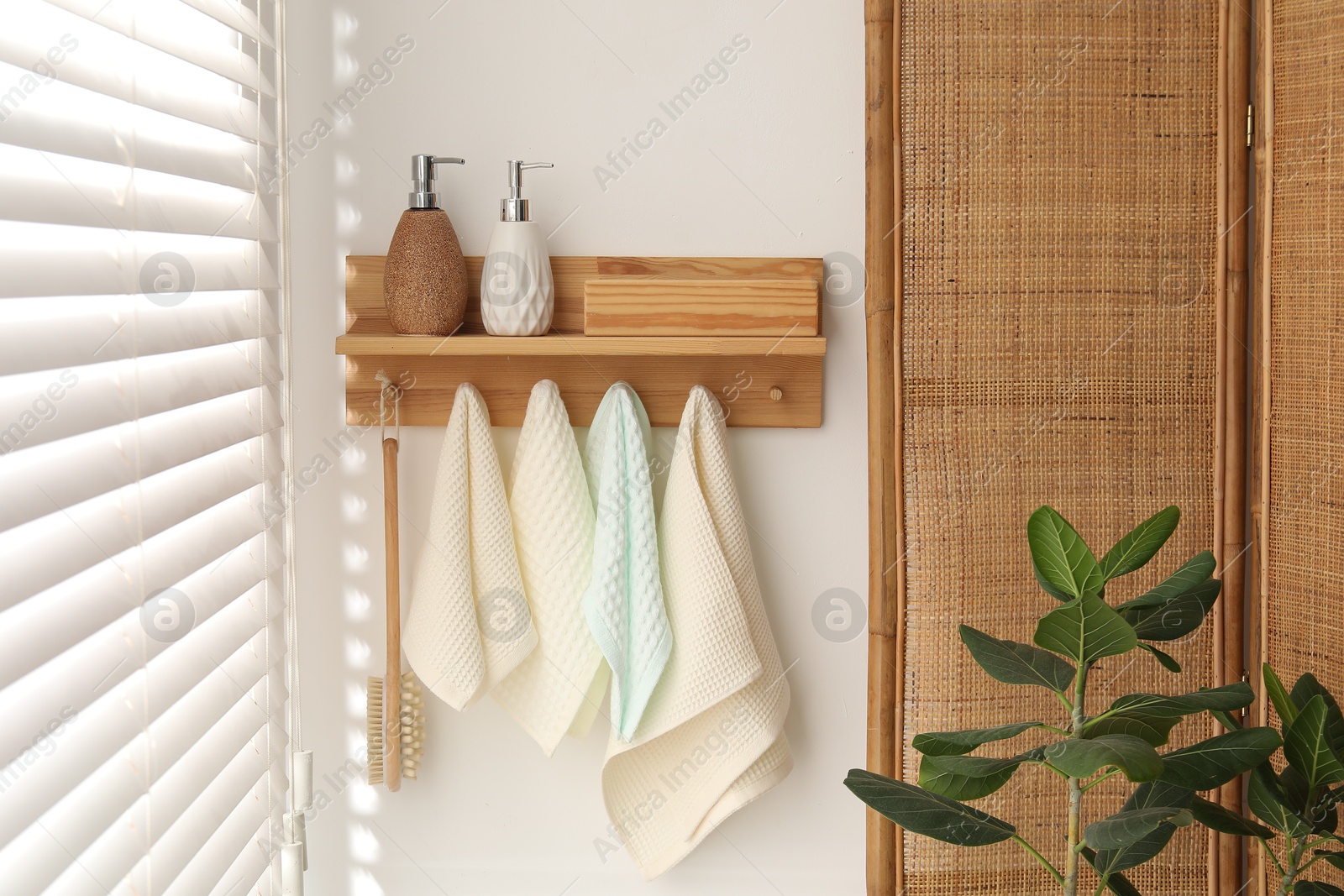 Photo of Clean waffle towels and brush hanging on hook rack in bathroom