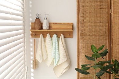 Photo of Clean waffle towels and brush hanging on hook rack in bathroom