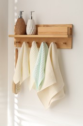 Photo of Clean waffle towels and brush hanging on hook rack in bathroom