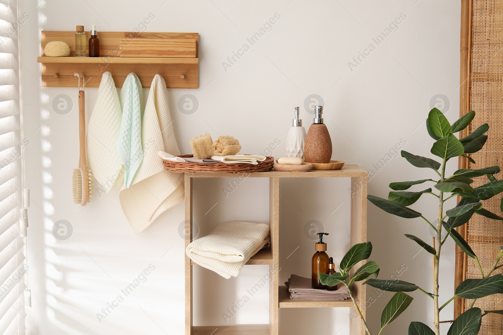 Photo of Clean waffle towels hanging on hook rack, brush and spa products in bathroom