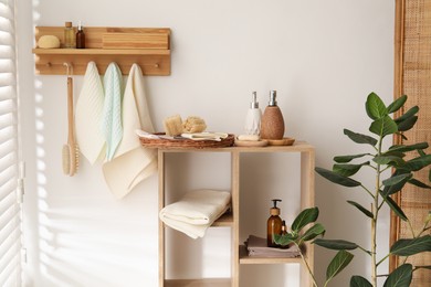 Photo of Clean waffle towels hanging on hook rack, brush and spa products in bathroom