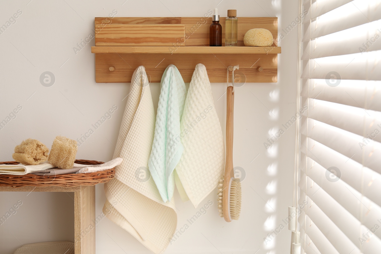 Photo of Clean waffle towels hanging on hook rack, brush and spa products in bathroom