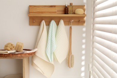 Photo of Clean waffle towels hanging on hook rack, brush and spa products in bathroom