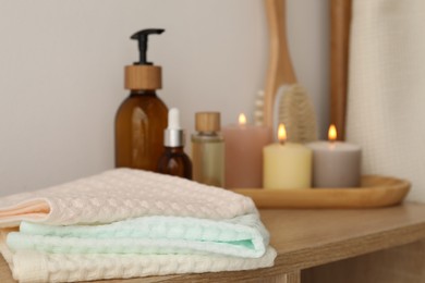 Photo of Clean waffle towels, burning candles and spa products on shelf in bathroom