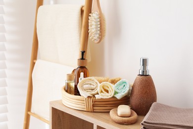 Photo of Clean waffle towels and spa products on shelving unit near white wall in bathroom
