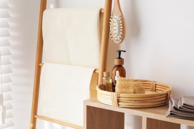 Photo of Clean waffle towels and spa products on shelving unit near white wall in bathroom