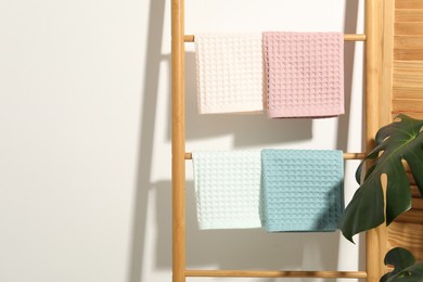 Photo of Clean waffle towels hanging on shelving unit near white wall. Space for text