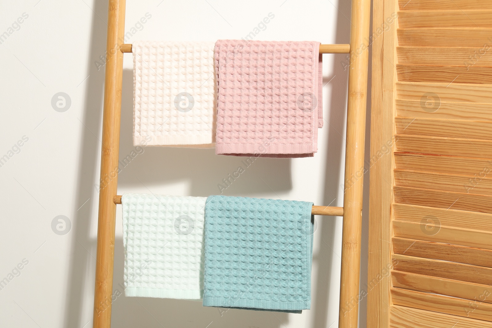 Photo of Clean waffle towels hanging on shelving unit near white wall