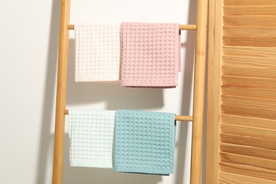 Photo of Clean waffle towels hanging on shelving unit near white wall