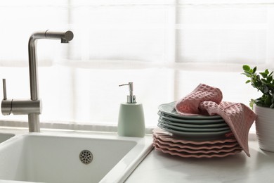 Photo of Pink waffle towel on stack of clean plates near sink