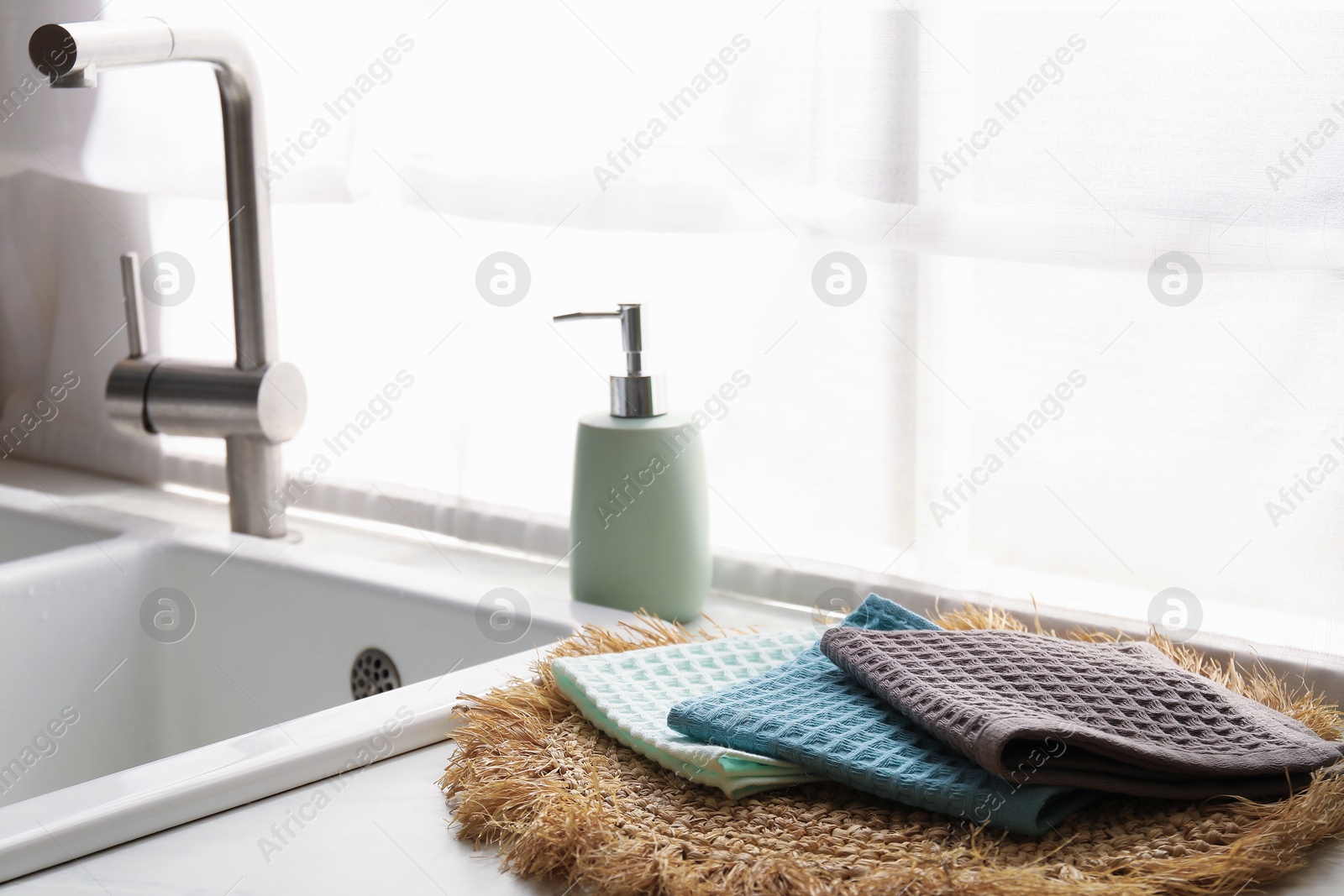 Photo of Clean waffle towels on wicker mat near sink, closeup