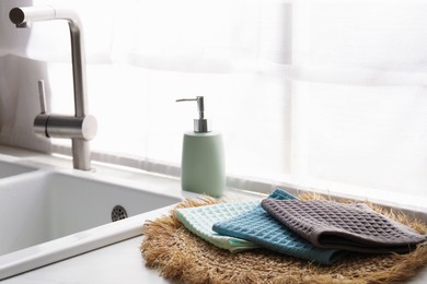Photo of Clean waffle towels on wicker mat near sink, closeup