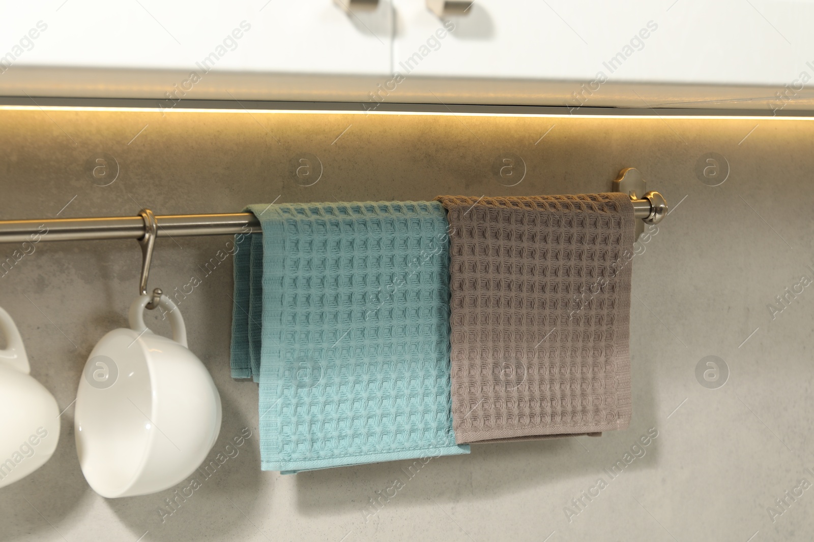 Photo of Clean waffle towels and cups hanging on hook rack indoors