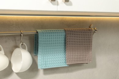 Photo of Clean waffle towels and cups hanging on hook rack indoors