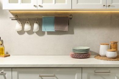 Photo of Clean waffle towels and cups hanging on hook rack above counter in kitchen