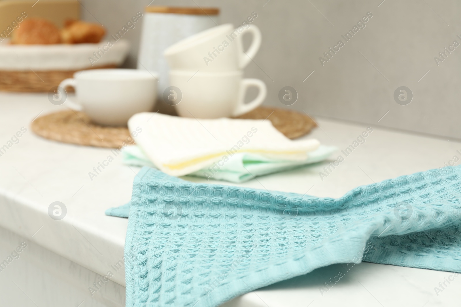 Photo of Waffle towels and dishware on white counter near grey wall, closeup