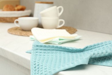 Photo of Waffle towels and dishware on white counter near grey wall, closeup