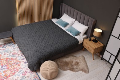 Photo of Large bed, nightstand and pouf in stylish bedroom, above view. Interior design