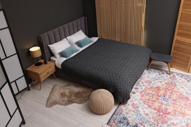 Photo of Large bed, nightstand and pouf in stylish bedroom, above view. Interior design