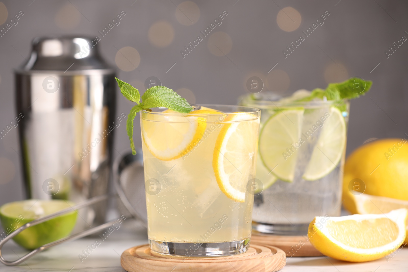 Photo of Tasty citrus cocktails in glasses on table against blurred lights, closeup