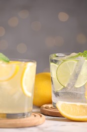 Photo of Tasty citrus cocktails in glasses on white table against blurred lights, closeup